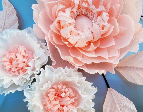 Exquisite paper art display, consisting of a large, detailed blush peony and three smaller, intricate white flowers, all with lifelike petal layers and texture, artistically arranged on a serene blue background to accentuate the delicate craftsmanship and