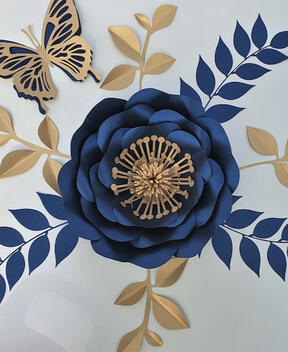 Navy blue and metallic gold paper flowers, meticulously designed with intricate details, available in varying sizes and accompanied by gold leaves for a chic and artistic decor enhancement.