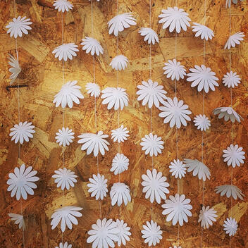 ersatile white floral garland made from pearl paper, with flowers ranging from 4 to 10 centimeters, strung gracefully on a cord for elegant shop windows or ceremonial arches